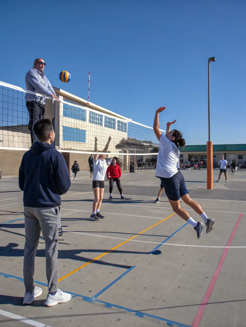 Students working together to set up equipment for a volleyball match, highlighting teamwork and responsibility.